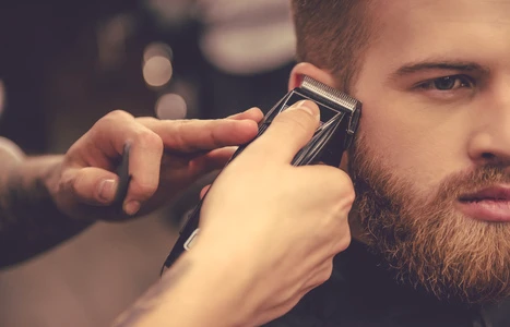 Ein Mann erhält eine Bart-Haar-Rasur von einem professionellen Friseur